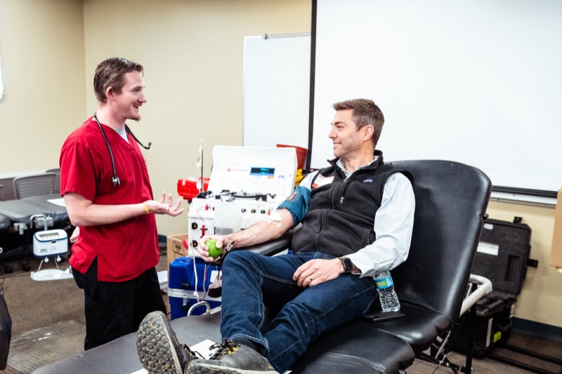 Health worker in scrubs talking with a donor at a campus blood drive
