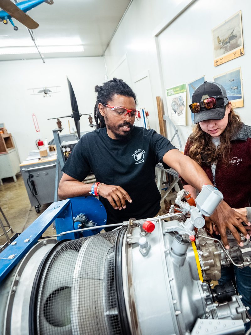 Aviation maintenance instructor working on a turbine engine with two students