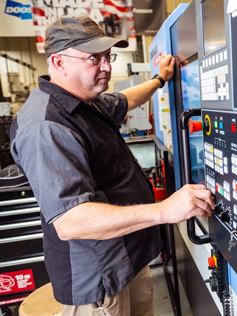 Machining instructor walking a student through the control panel of a CNC lathe