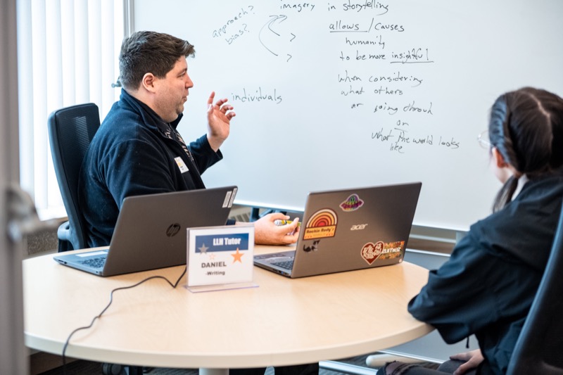 Two people working through notes and laptops at a campus meeting table