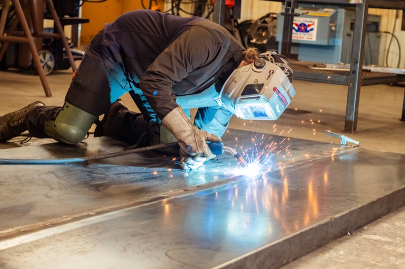 Welding student cutting steel plate, sparks flying across the shop floor